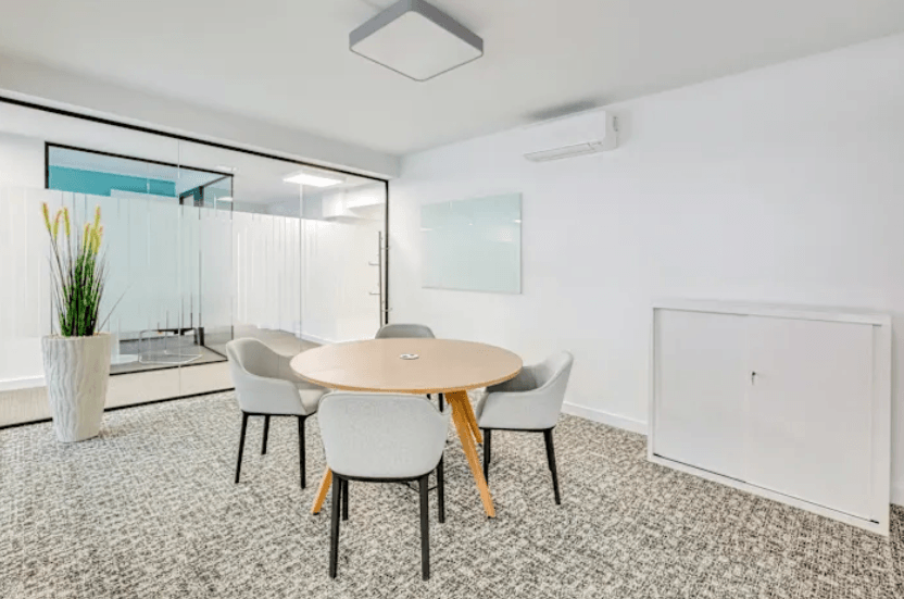 Helles Besprechungszimmer mit rundem Tisch, Stühlen und Glaswand